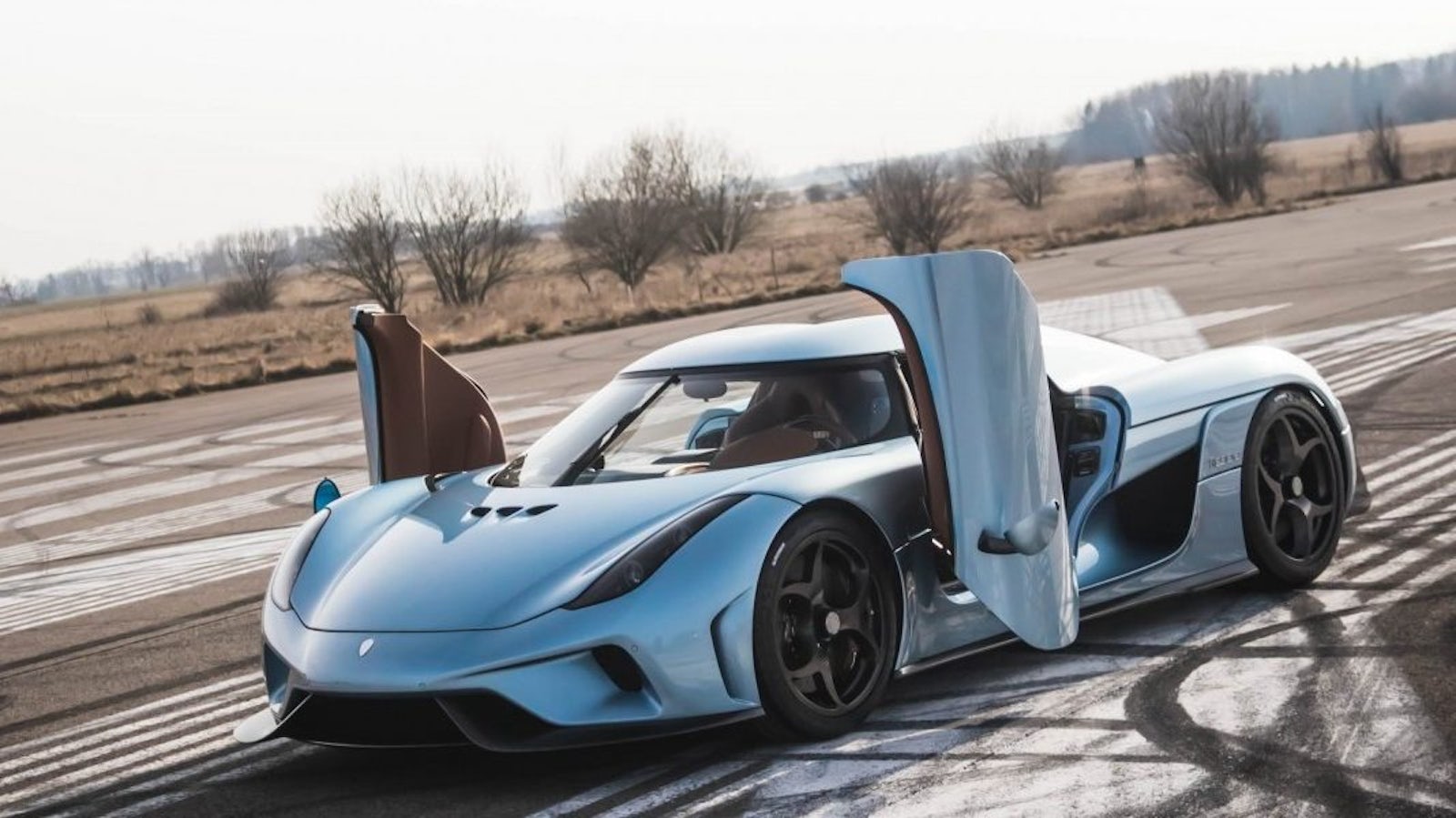 A Koenigsegg Regera hypercar positioned on an open airstrip.