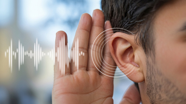 An individual listening carefully with a sound wave graphic representing audio perception.