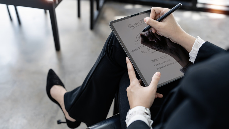 A woman comfortably writing on a slim E Ink tablet using a stylus.