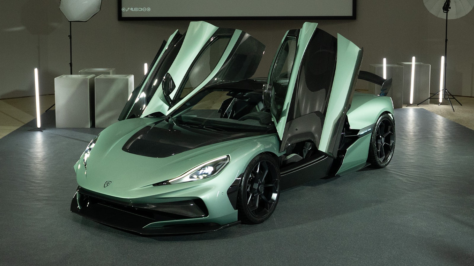 The green Rimac Nevera R electric hypercar parked on a racing circuit.