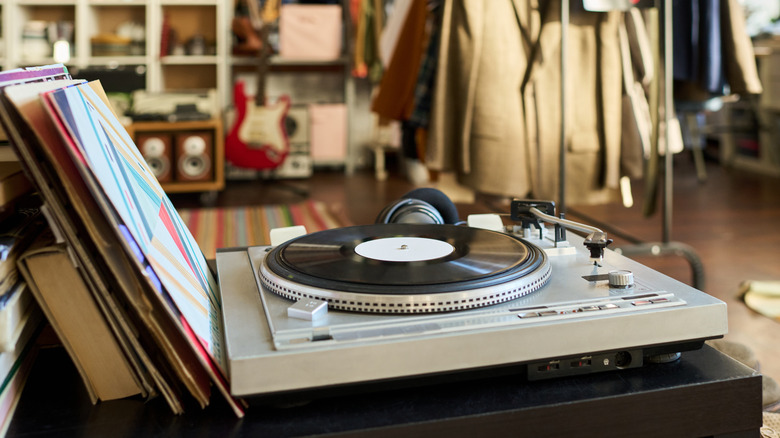 A vinyl record spinning on a turntable surrounded by album sleeves and audio equipment.