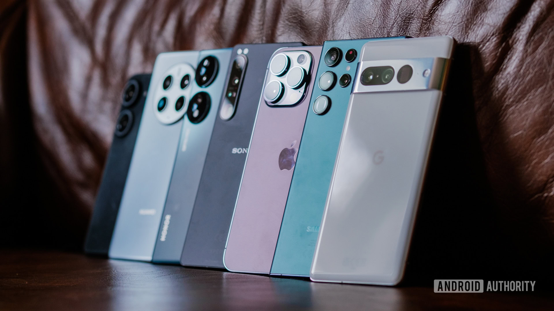 A collection of various high-end smartphones laid out on a leather surface.