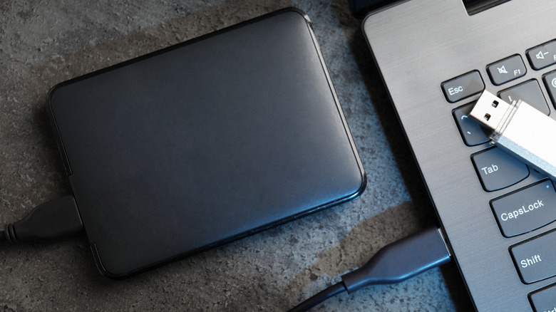 A USB flash drive and an external SSD drive placed next to a computer.