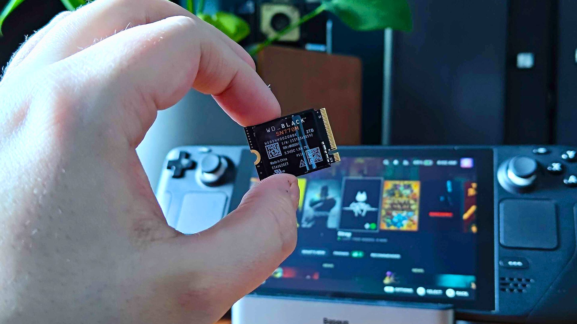 A person holding a tiny WD Black SN770M M.2 2230 SSD specifically designed for handheld gaming PCs.