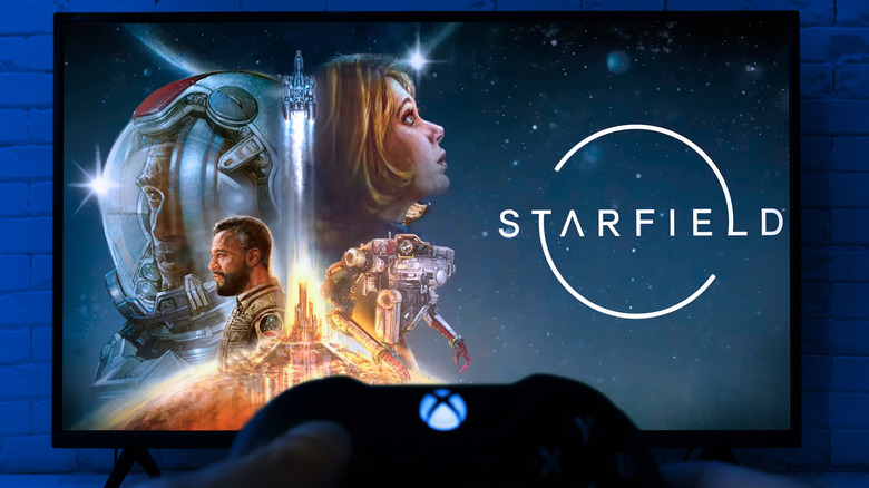 A person holding a wireless Xbox controller while facing a smart TV screen.