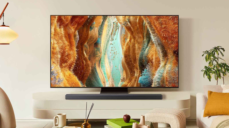 A large Samsung flat-screen TV mounted on a minimalist wall in a bright room.