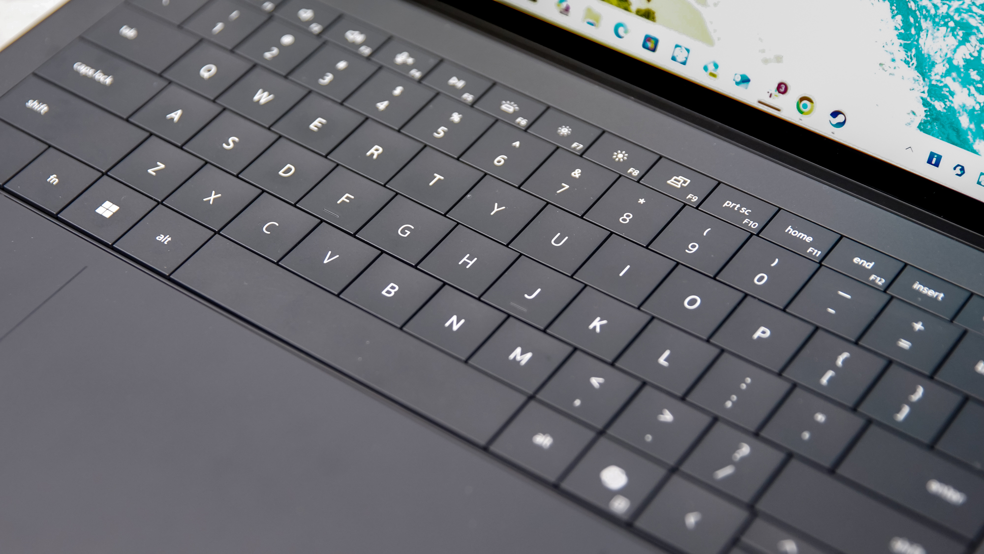 Close-up detail of the Dell XPS 14 keyboard and the etched boundaries of the haptic trackpad.