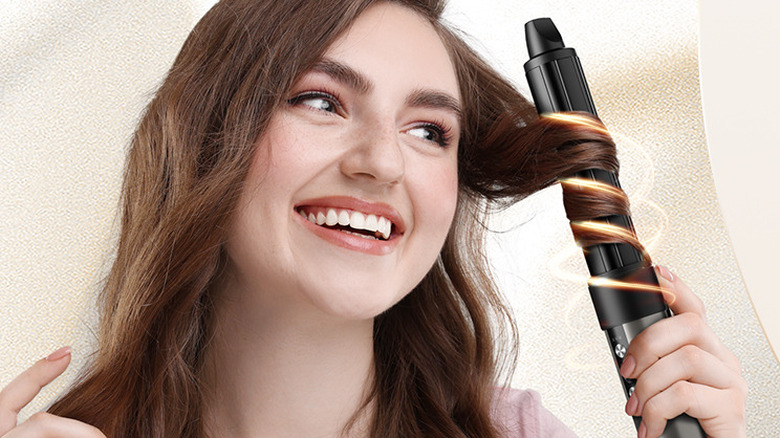 A person using the 7MAGIC multi-styler to curl a section of hair.