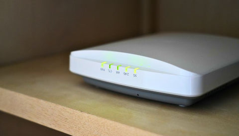 Close-up of a modern Wi-Fi router and network equipment with blue status lights.