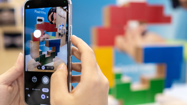 A person holding a Pixel phone horizontally to capture a professional-grade photograph outdoors.