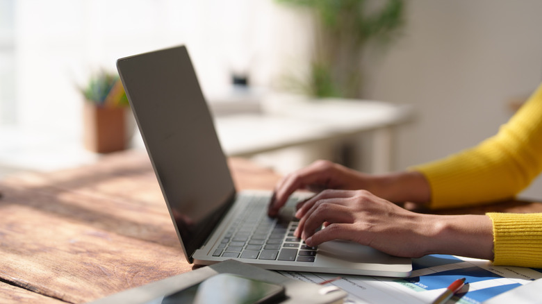 A close-up shot of a person's hands typing on a laptop, representing a remote workspace.