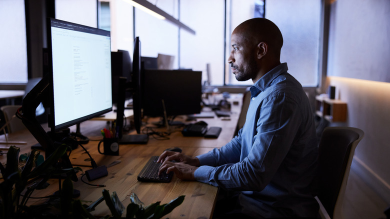 A man focused on his work using a modern desktop computer setup.