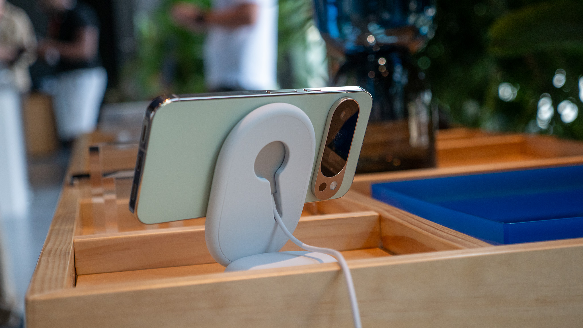The official Pixelsnap Qi2 wireless charger standing next to a Google Pixel 10.