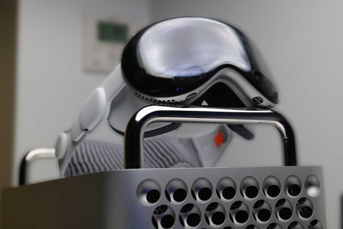 A user wearing an Apple Vision Pro headset while working on a Mac Pro