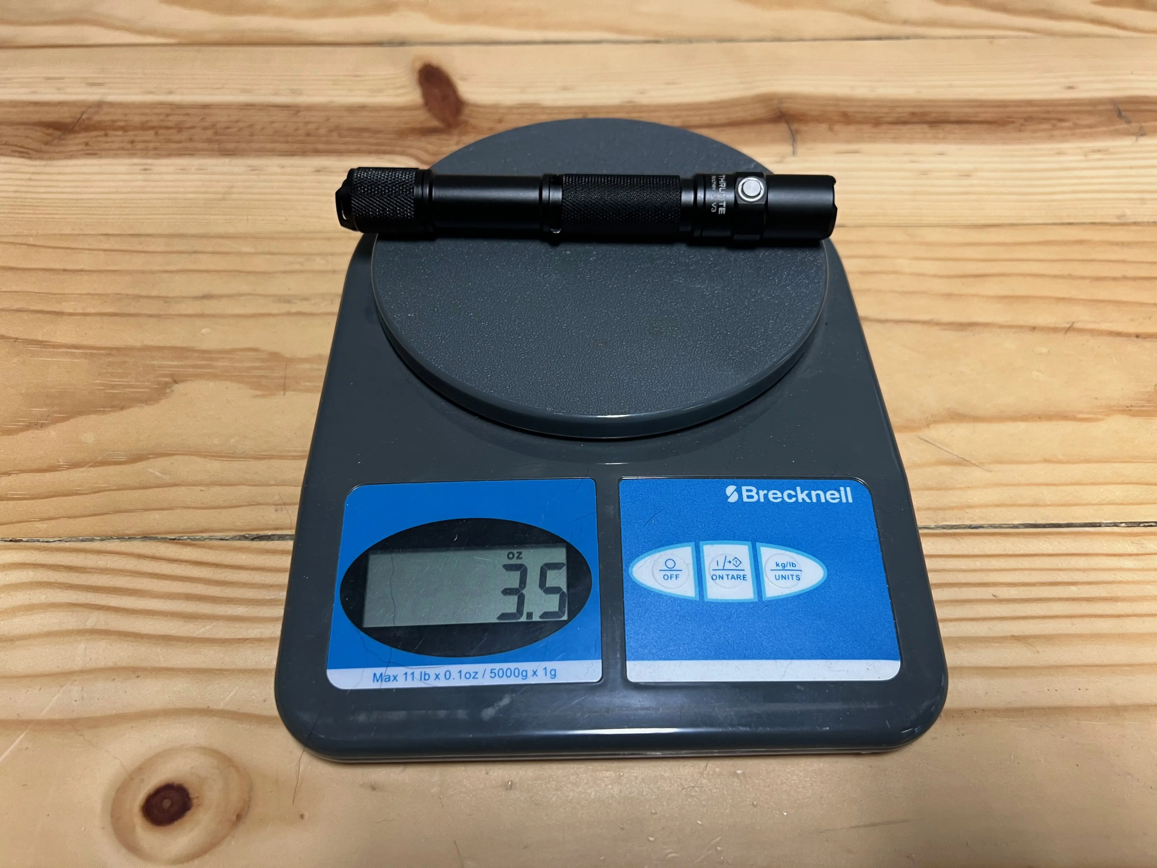 A small flashlight being weighed on a digital scale for precision testing.