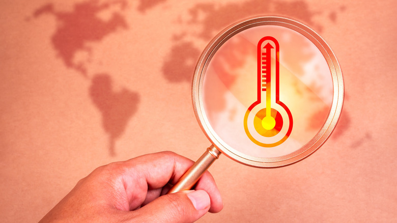 A magnifying glass focusing on a temperature sensor with a world map in the background.