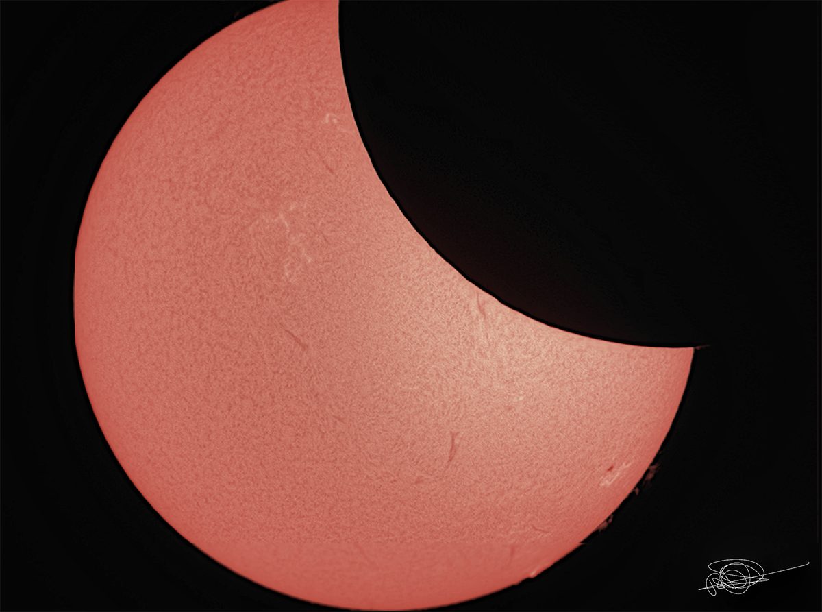 A telescope view of a partial solar eclipse with a black curve biting into the solar disk.