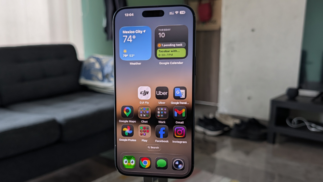 The front display of a slim iPhone being held, showing the 6.9-inch Super Retina XDR screen.