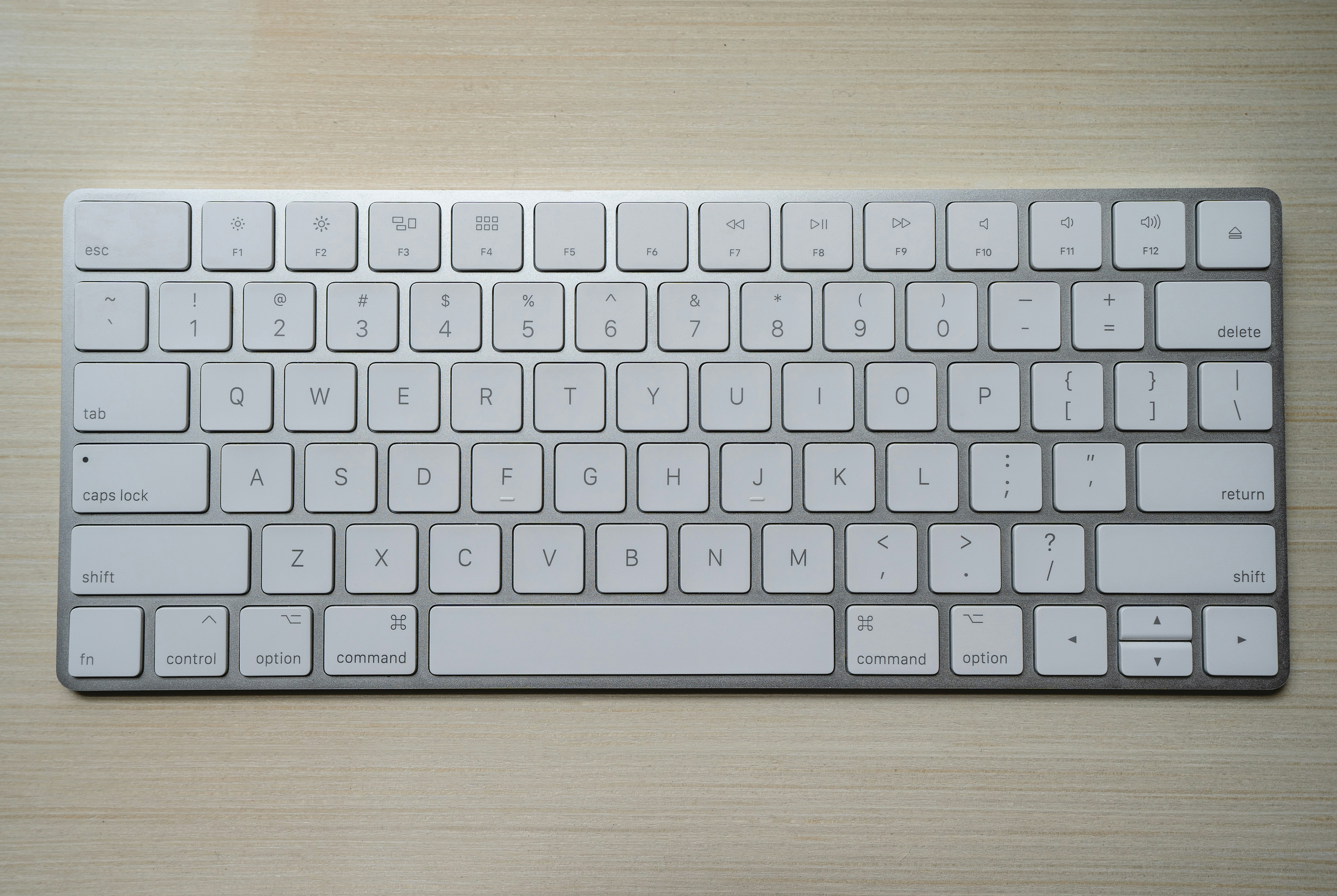 A white mechanical wireless keyboard with soft RGB lighting on a desk.