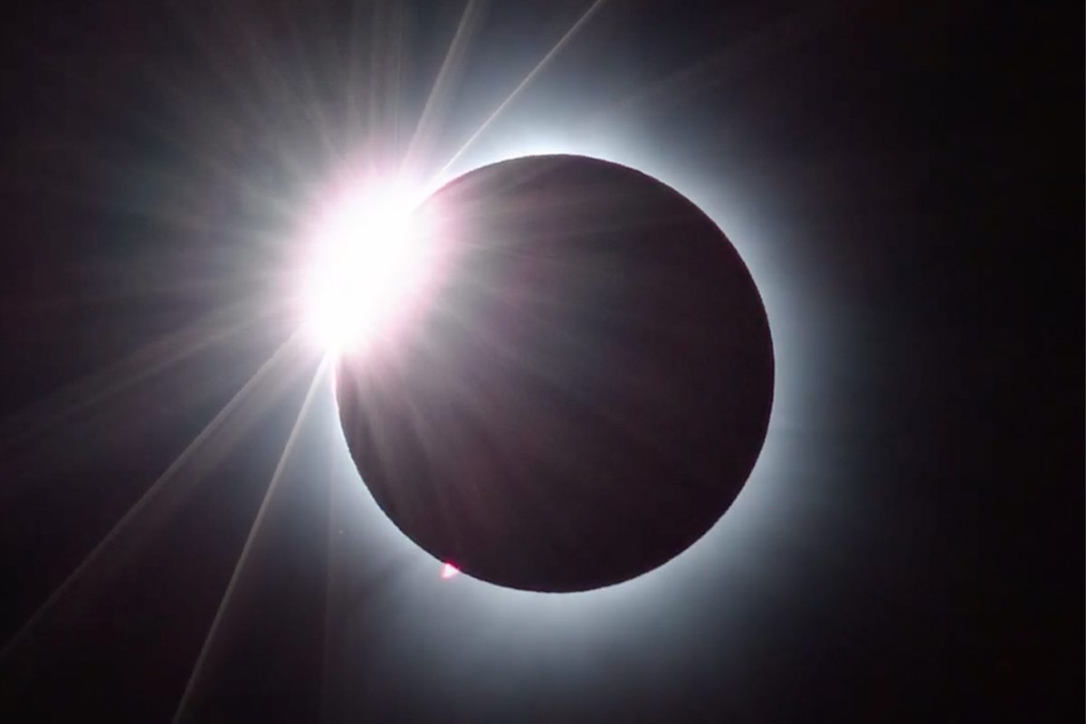 A total solar eclipse with a glowing white corona surrounding the black silhouette of the moon.