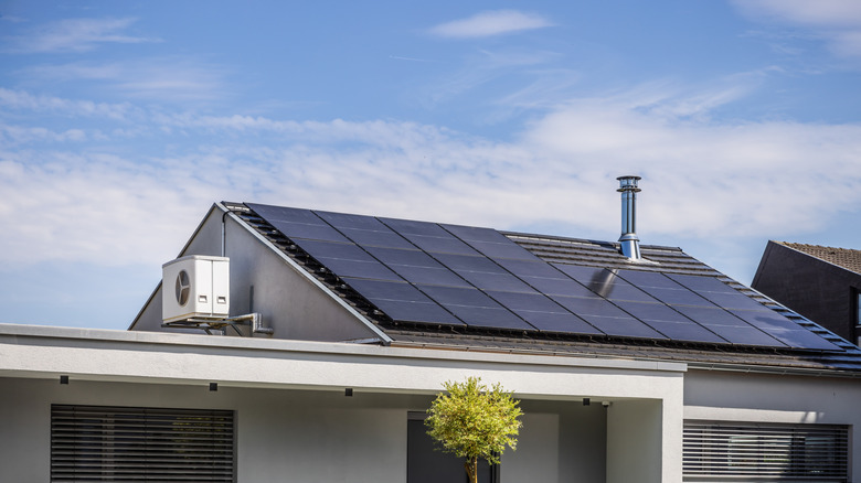 Residential solar panel installation on a roof featuring a visible inverter system and air conditioning unit.