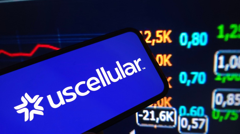 The US Cellular logo displayed on a mobile phone screen with financial data in the background.