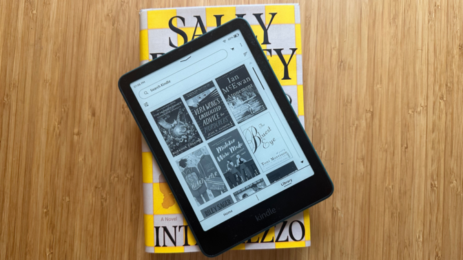 A close-up of the 2024 Amazon Kindle Paperwhite resting on several physical books.
